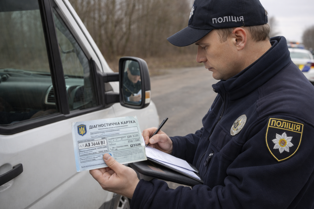 Поліцейський перевіряє документи і техогляд автомобіля під час дорожньої перевірки в Україні