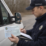 Поліцейський перевіряє документи і техогляд автомобіля під час дорожньої перевірки в Україні