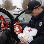 Поліцейський перевіряє аптечку, вогнегасник і знак аварійної зупинки в автомобілі під час зупинки в Україні