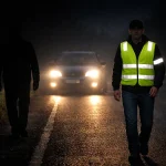 пішохід зі світлоповертальним жилетом і пішохід без відбивачів на темній дорозі