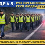 організована група людей рухається колоною по дорозі із супровідниками з ліхтарями