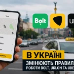 Смартфон із застосунками Bolt, Uklon та Uber на тлі таксі в центрі Києва